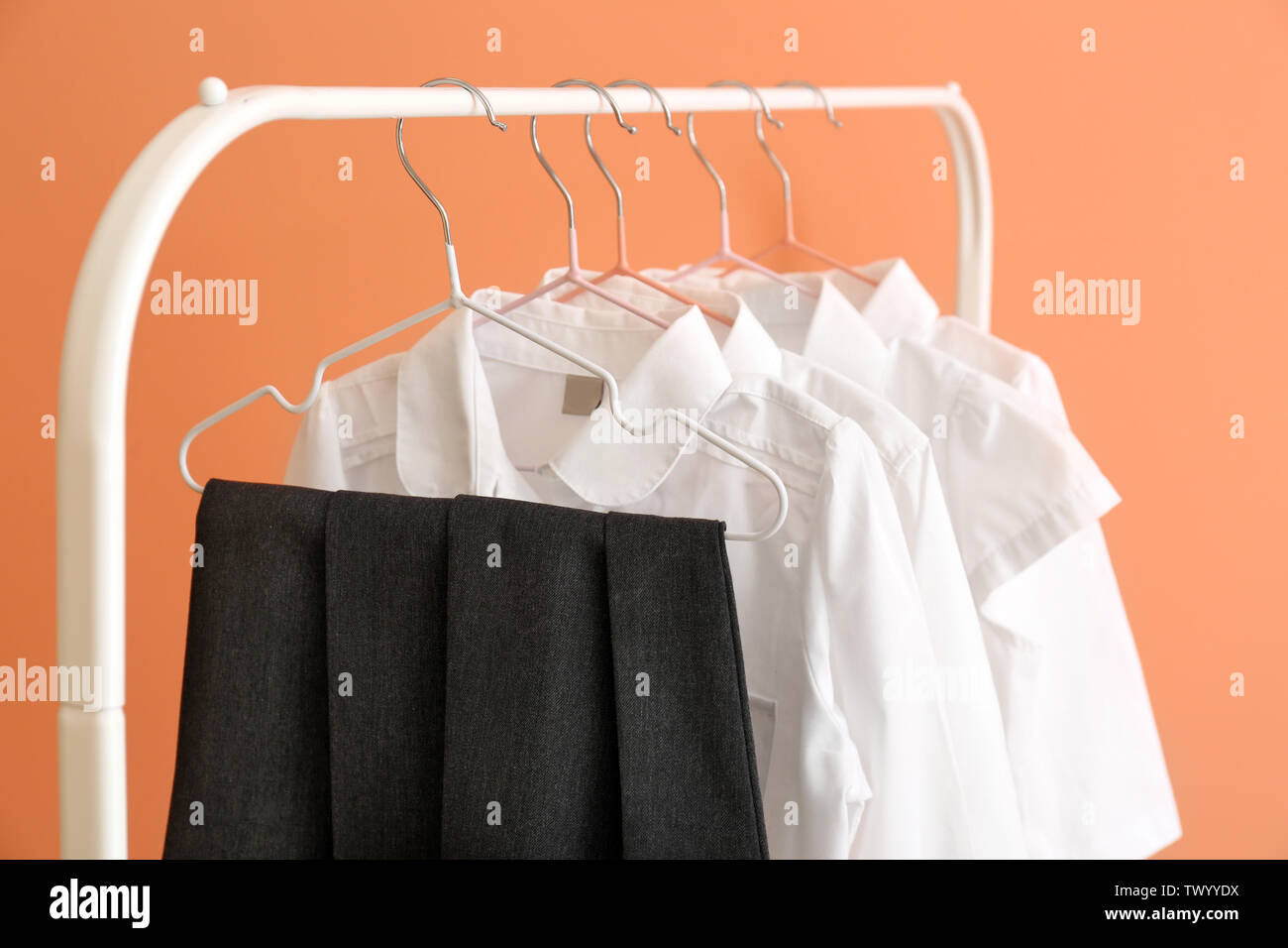 Stylish school uniform hanging on rack against color background Stock