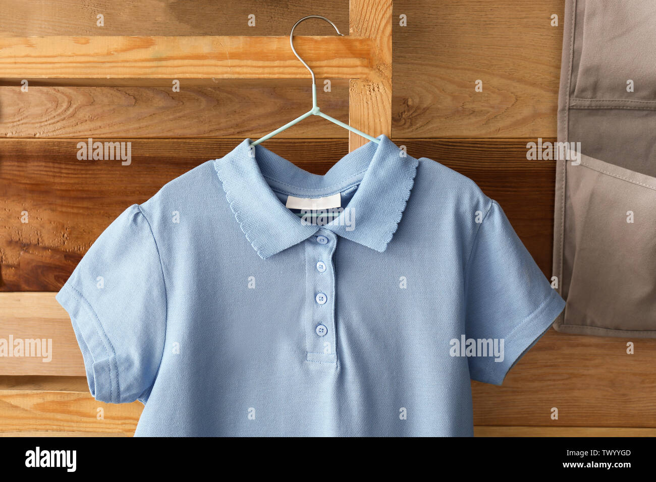 Stylish school uniform hanging on rack near wooden wall Stock Photo Alamy