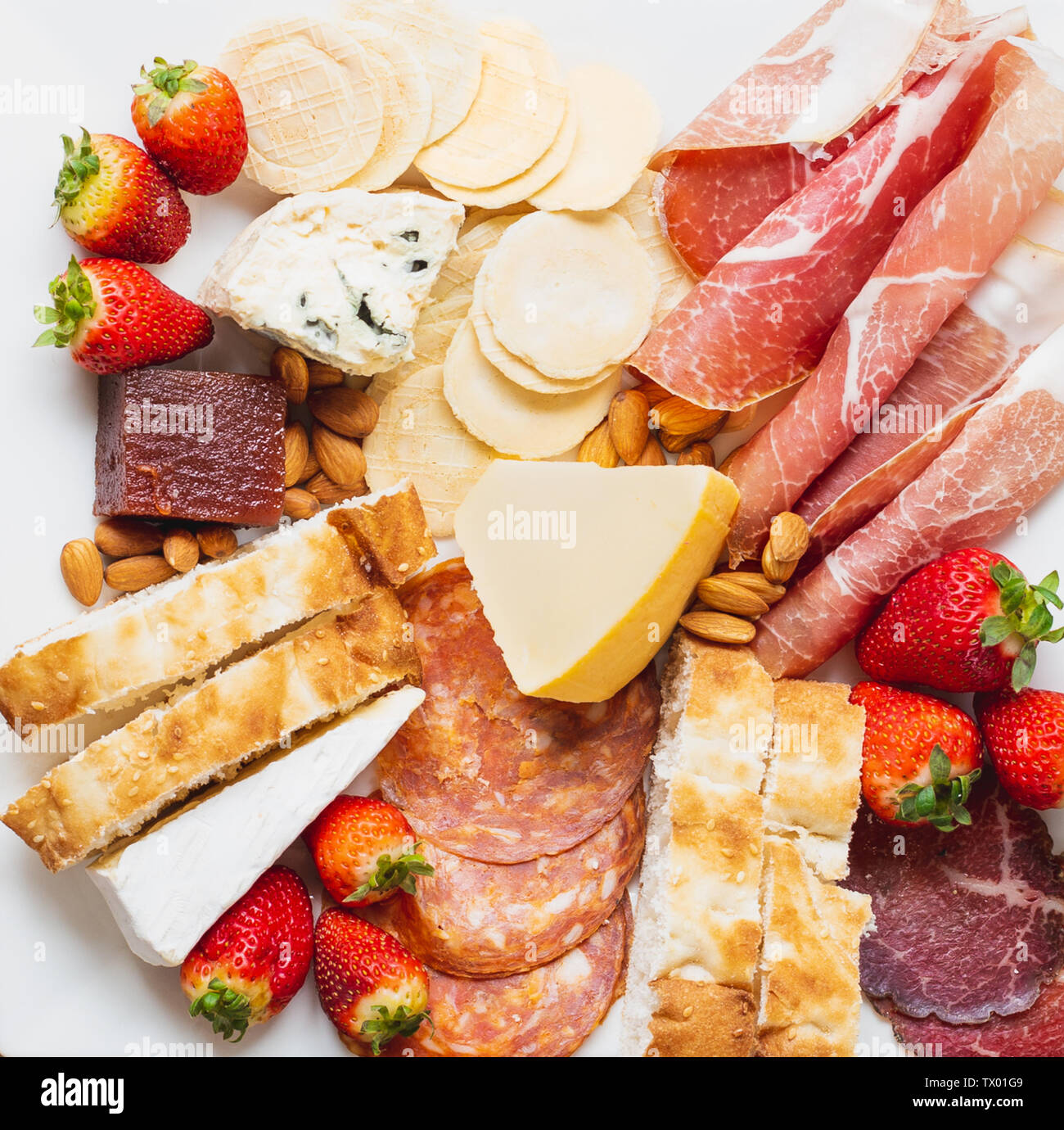 Overhead image of an antipasto platter with a mixture of cold meats, strawberries, cheese, crackers and bread Stock Photo
