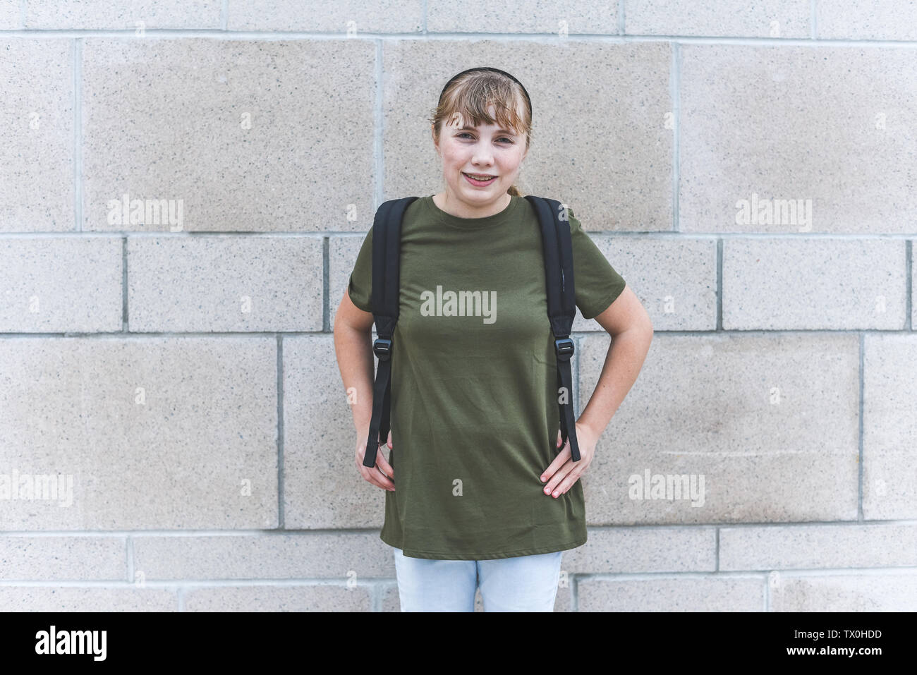 Happy teenage girl standing in front of brick wall Stock Photo - Alamy