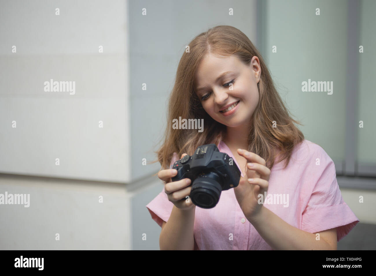 Portrait of young caucasian woman photgrapher holding a digital camera, smiling Stock Photo