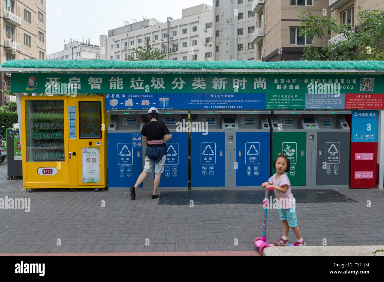 A woman places rubbish into one of the smart garbage-sorting dustbins in a residential compound in Beijing, China. Jun 23, 2019 Stock Photo
