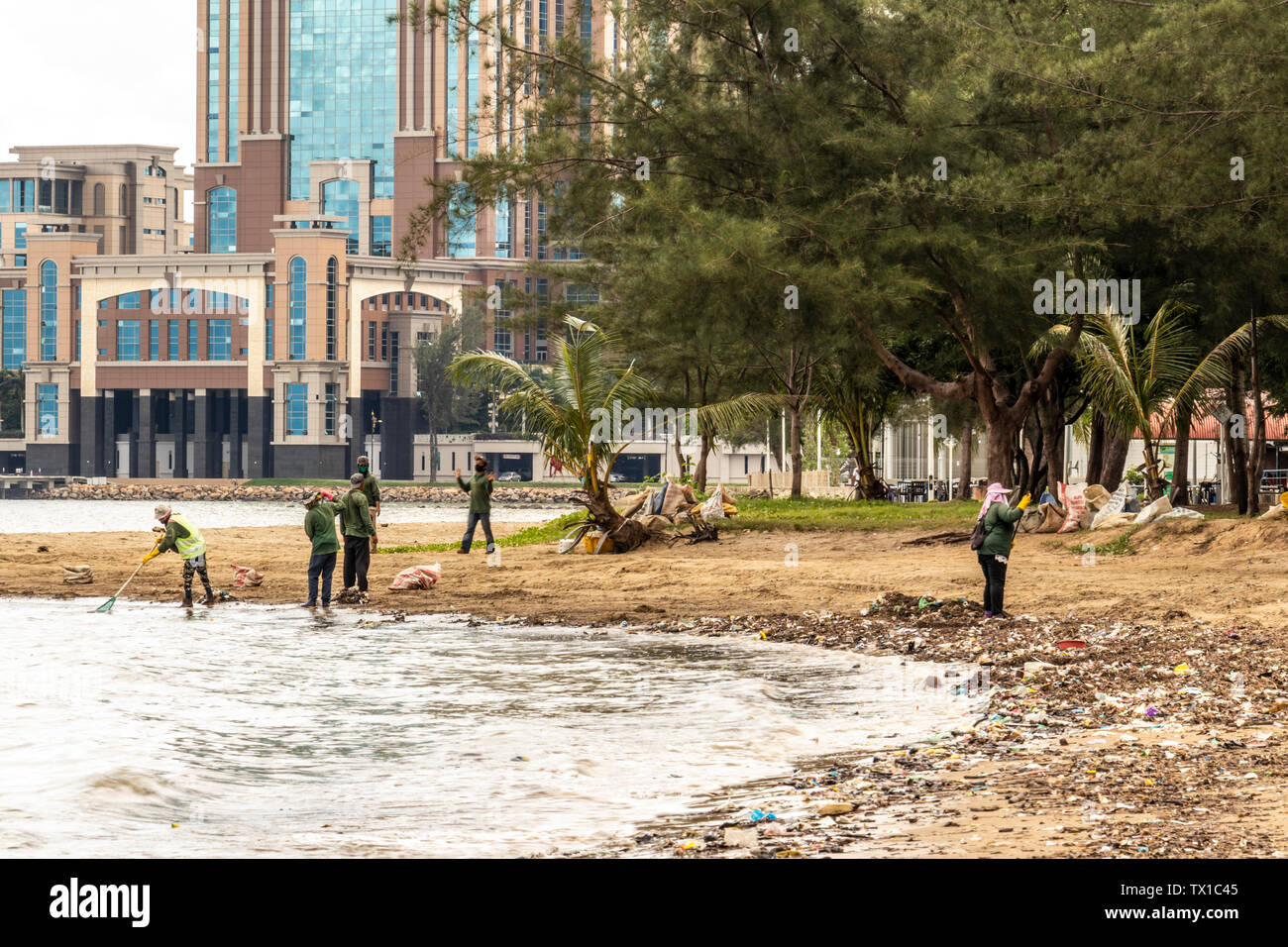 Workers cleaning up the beach at Likas Bay Kota Kinabalu Sabah Malaysia