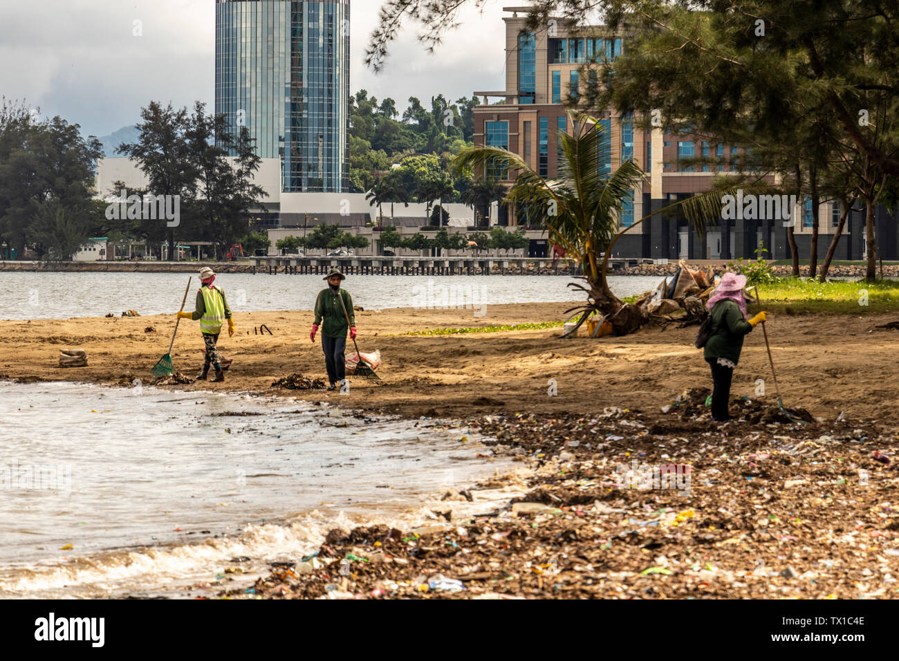 Workers cleaning up the beach at Likas Bay Kota Kinabalu Sabah Malaysia