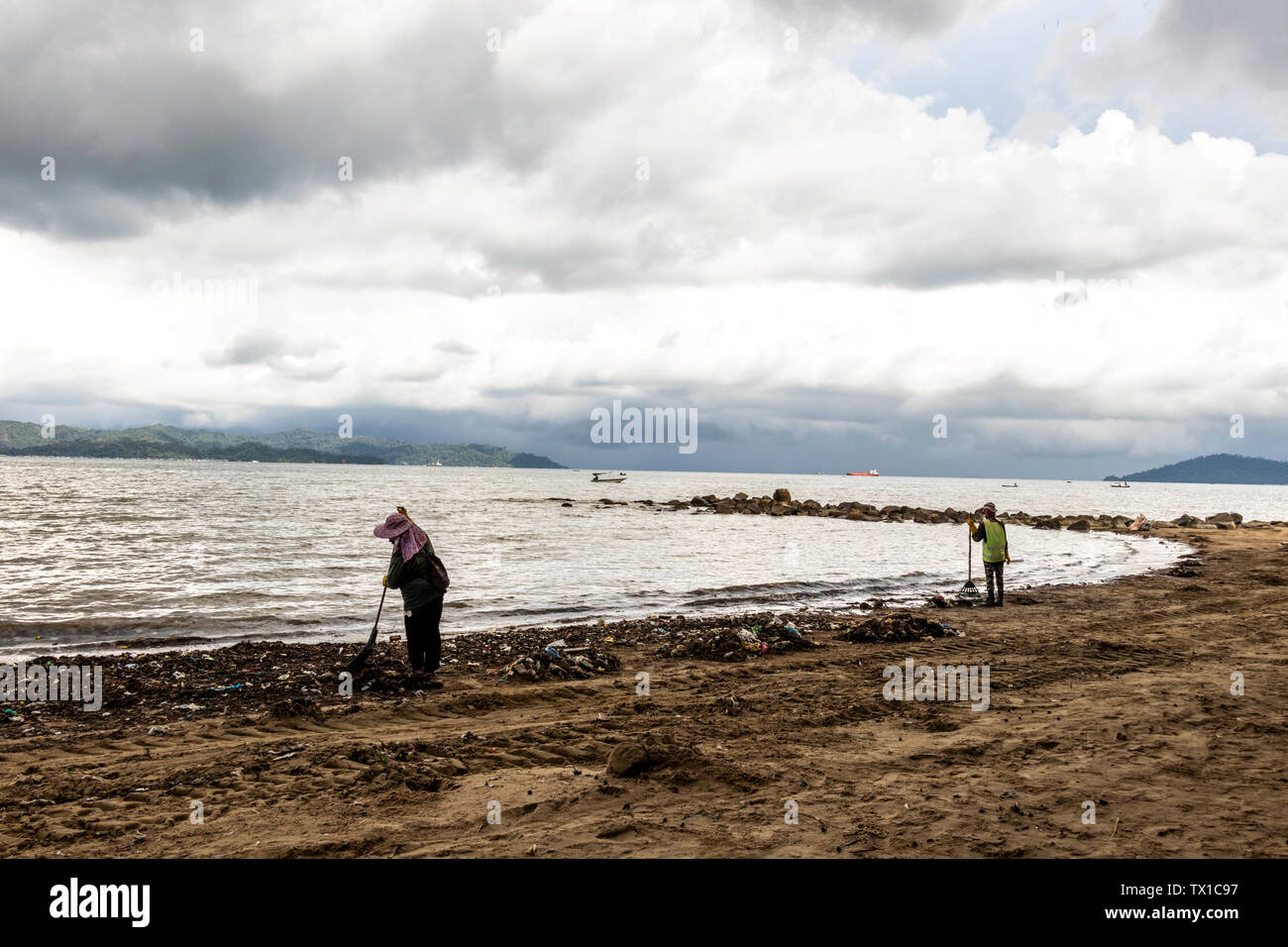 Workers cleaning up the beach at Likas Bay Kota Kinabalu Sabah Malaysia