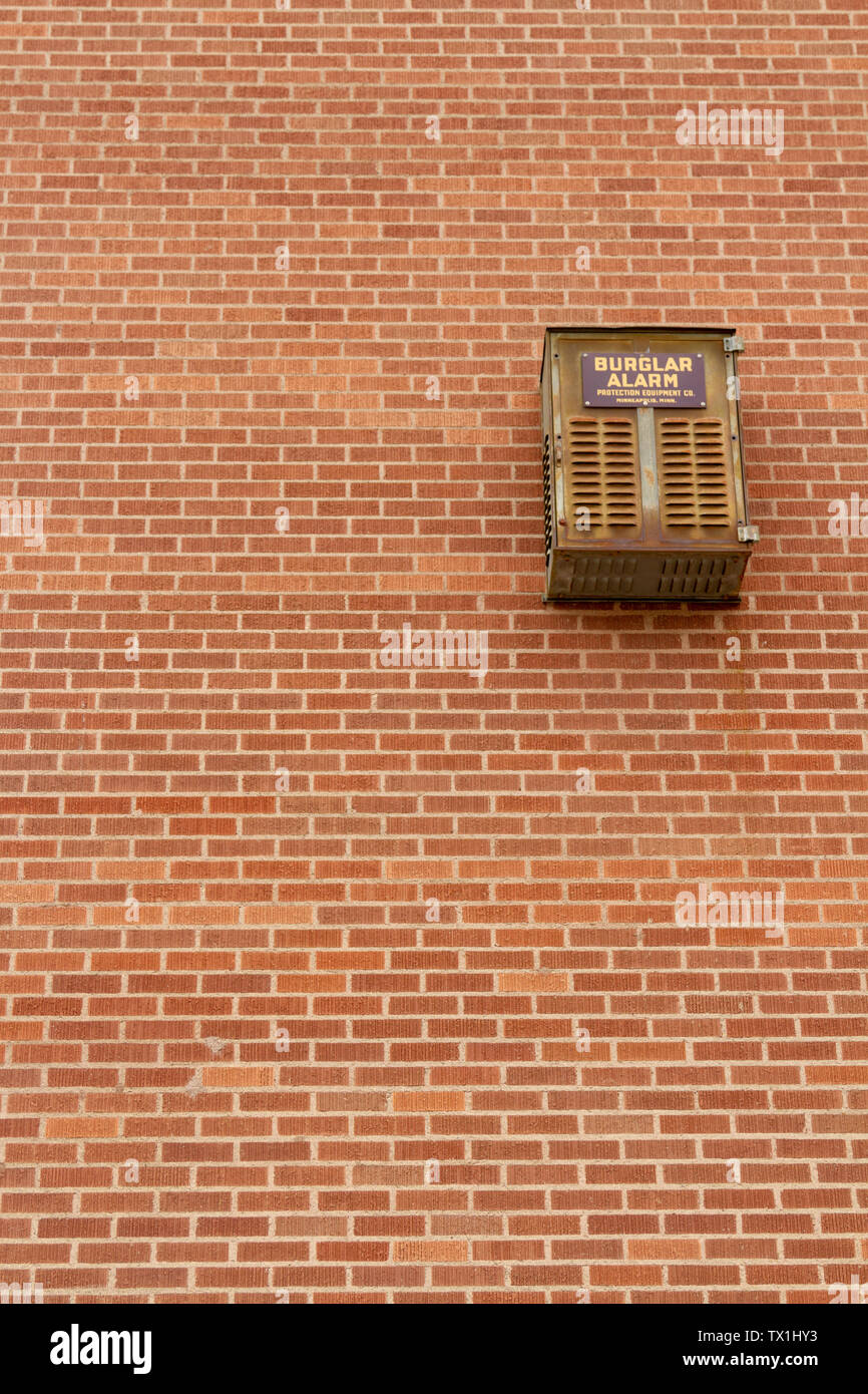 An out dated burglar alarm, made by Protection Equipment Co., hangs on the exterior of a brick building in downtown Helena, Montana, USA. Stock Photo