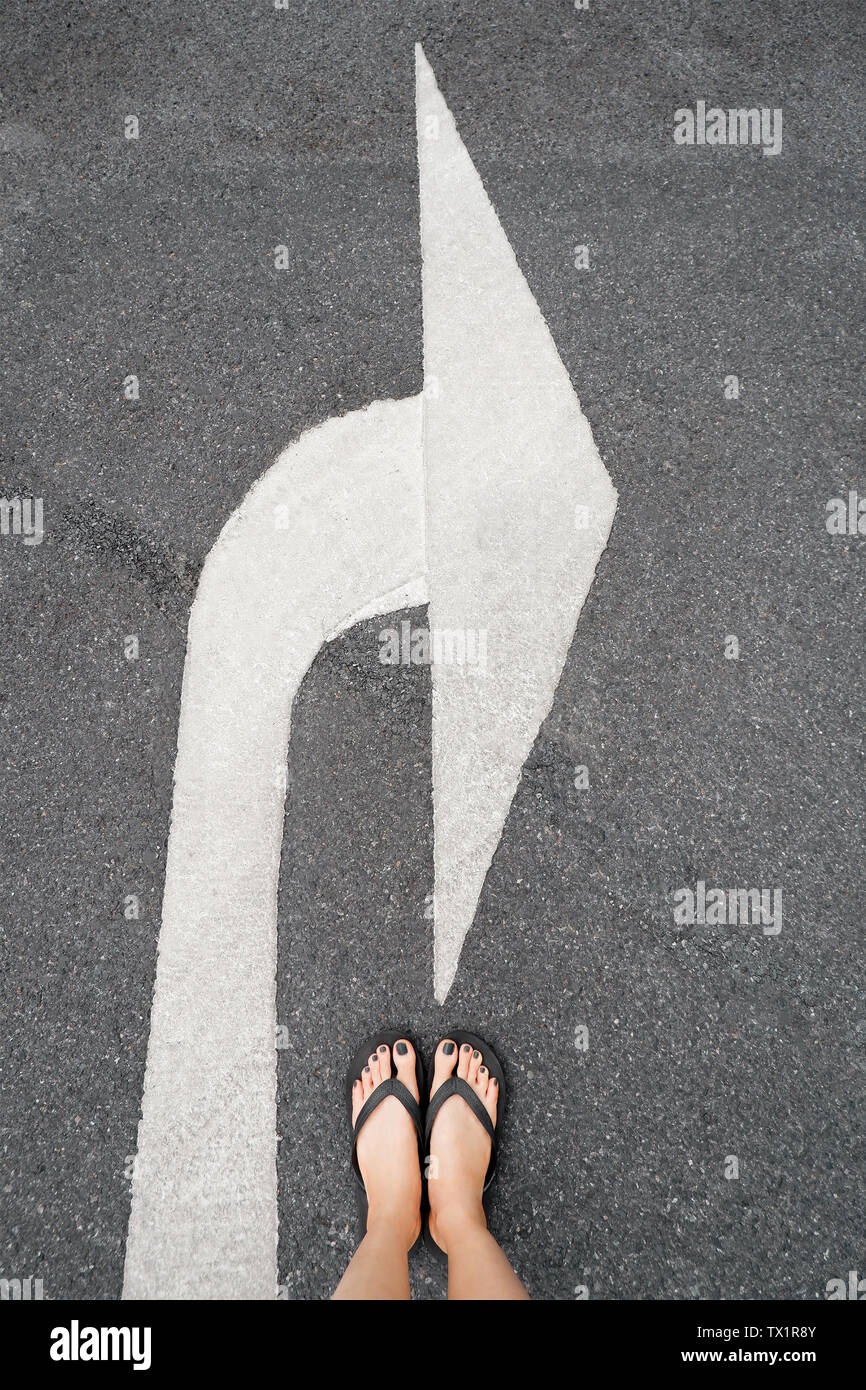 Turn Right Traffic Symbol. Feet and Arrows on Road Background. Woman Black Shoes or Sandals with Black Nail Polish Manicure Standing on the White Road. Stock Photo