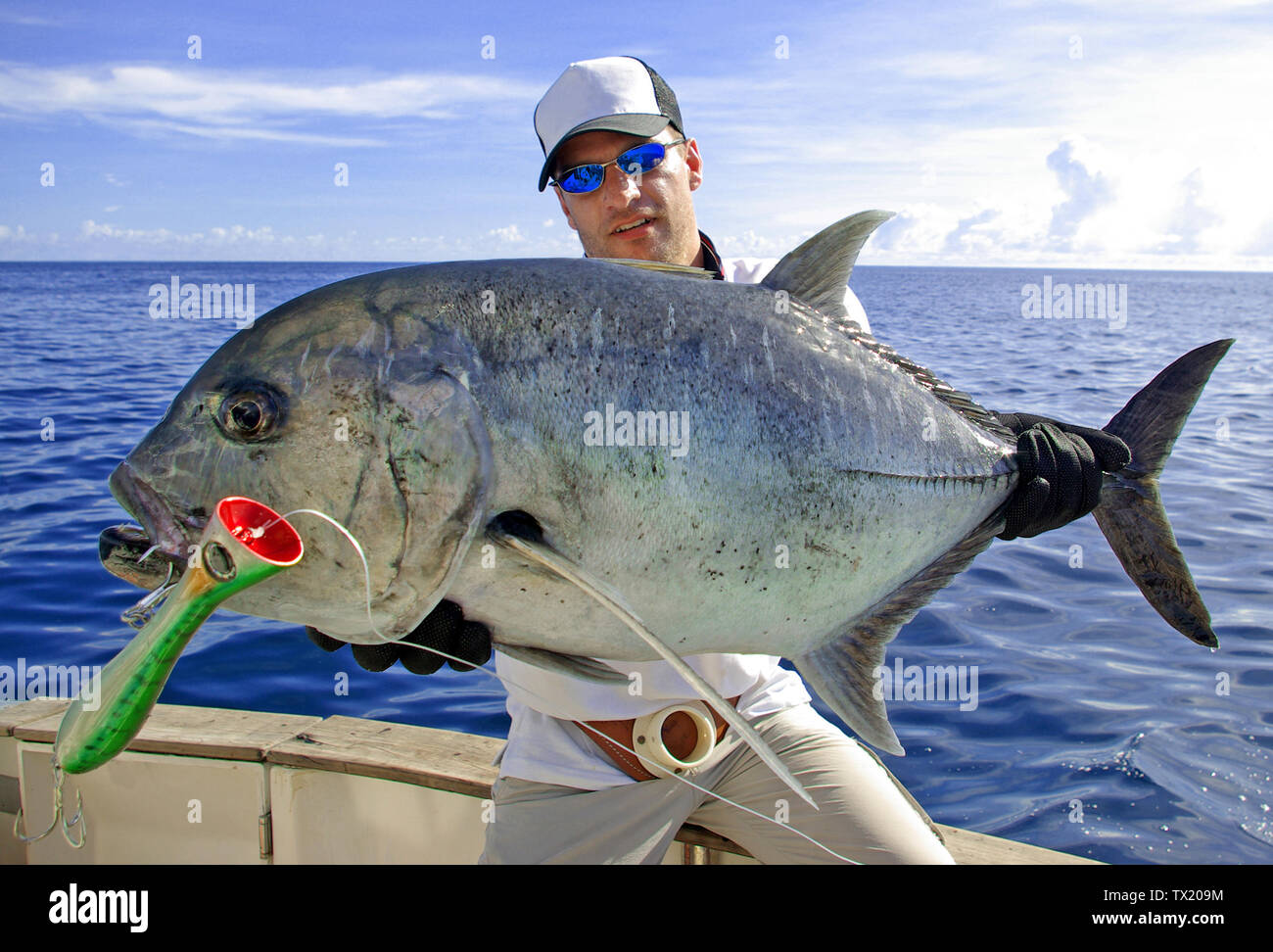 Deep sea fishing. Catch of fish. Big game fishing, boat fishing, lure fishing, sea fishing. Happy  fisherman holding a big Trevally jack Stock Photo