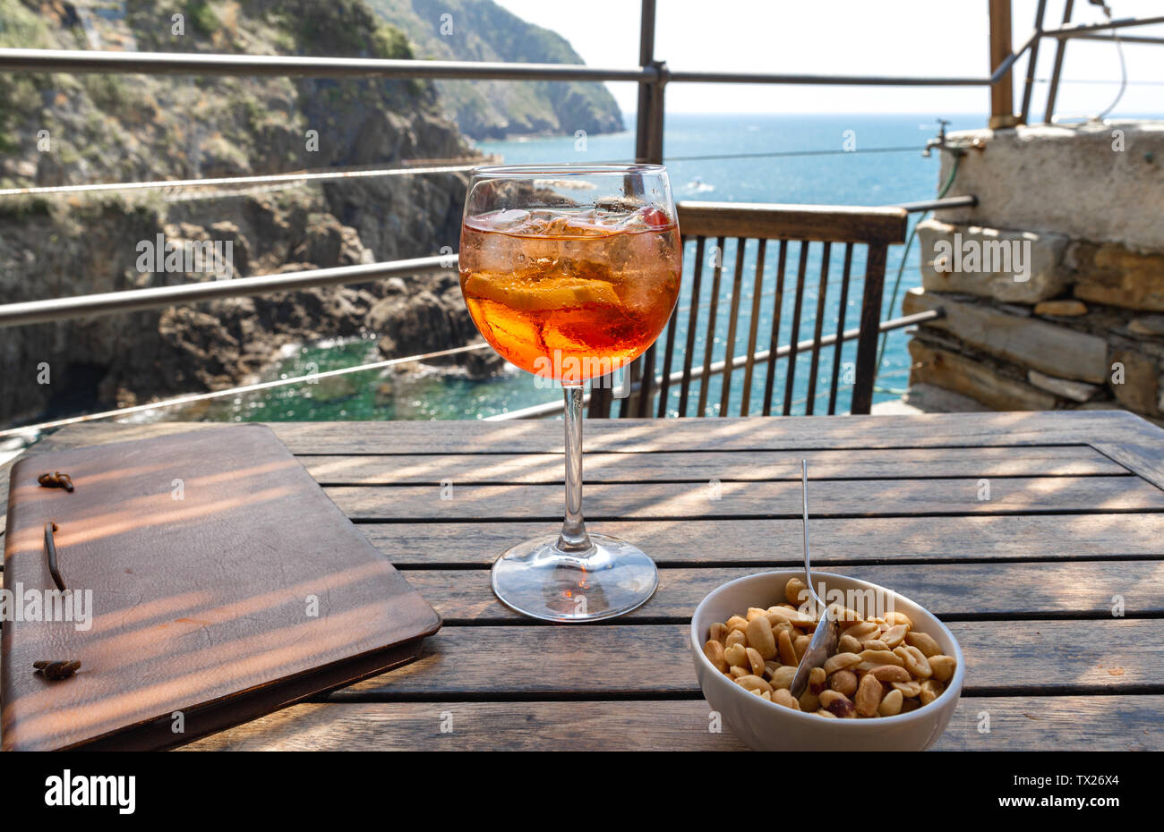 Aperol spritz cocktail close up on a wooden table in a restaurant. Riomaggiore in Cinque Terre, Italy Stock Photo