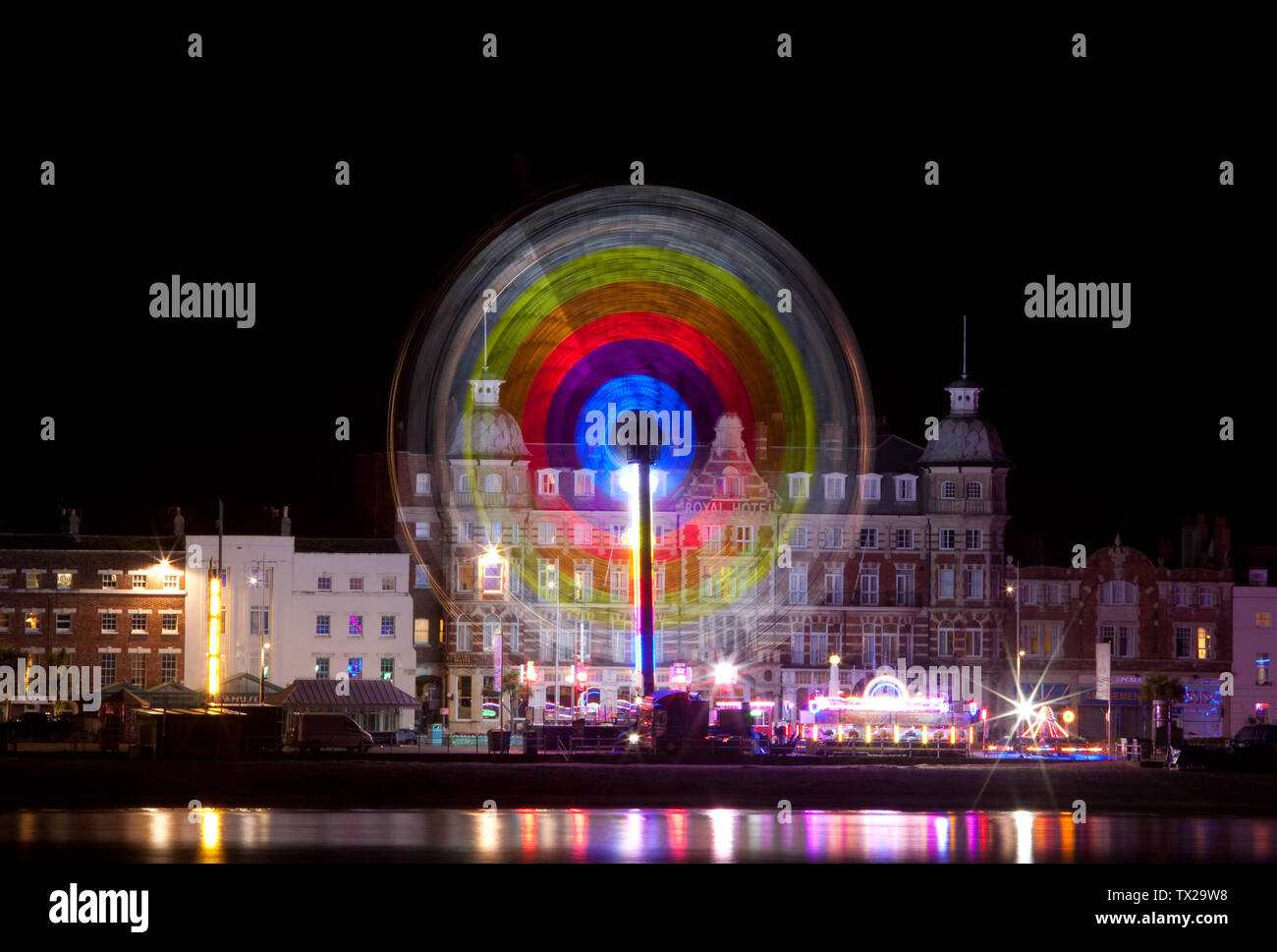 A long exposure photograph of the Oxygen Funfair Ride in front of The Royal Hotel on the Esplanade , Weymouth Dorset England Stock Photo