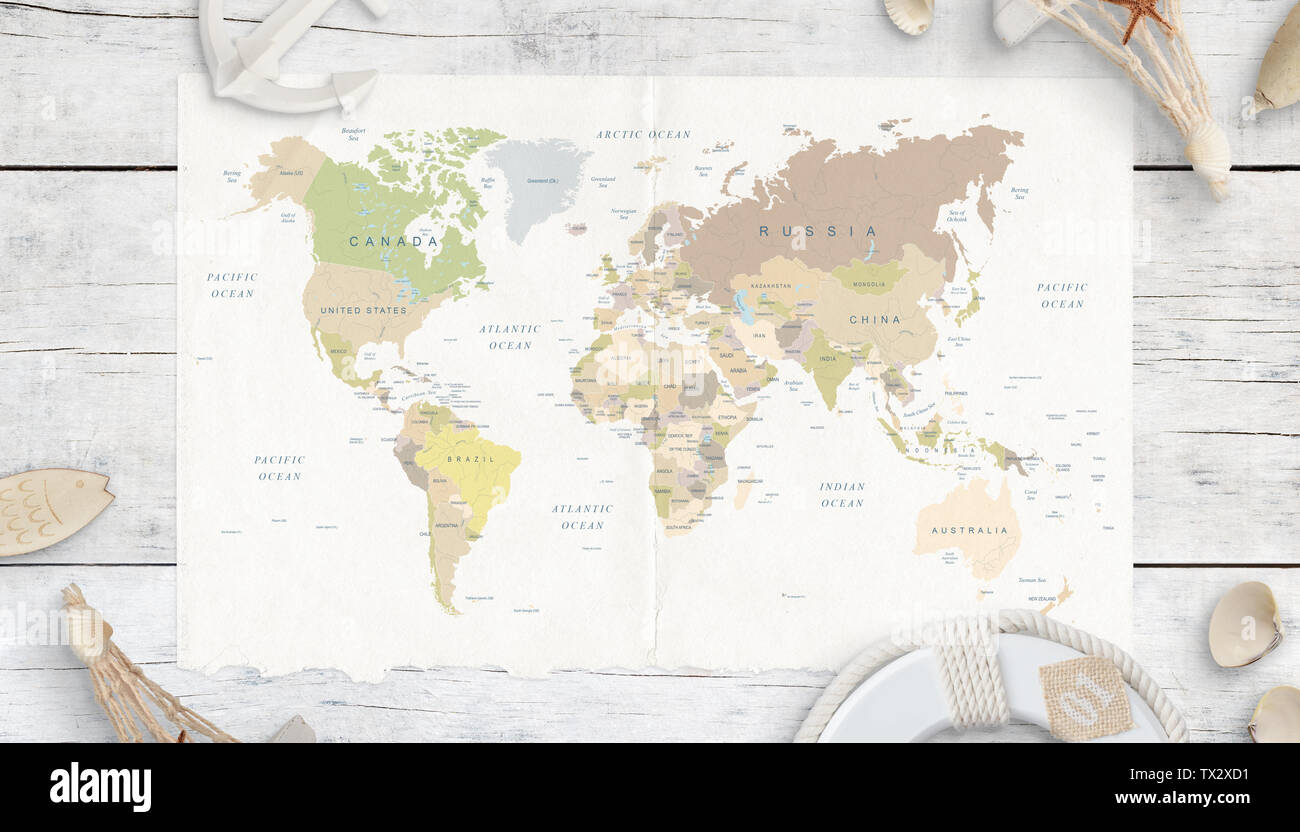 World map on white wooden table. Travel concept. Map surrounded with shells, anchor, lifebelt and souvenirs. Top view. Stock Photo