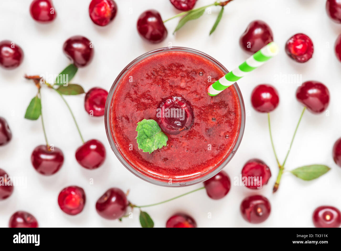 refreshment cherry smoothie in a glass with a straw and fresh berries on white background. top view. summer drink. healthy vegan diet Stock Photo