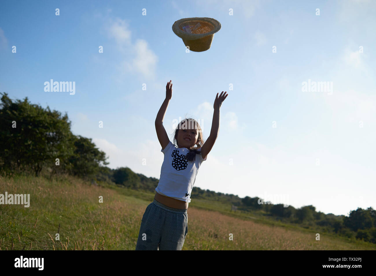 Stunning shots of a young Asian girl wearing a straw hat in summer sunshine blowing bubbles Stock Photo