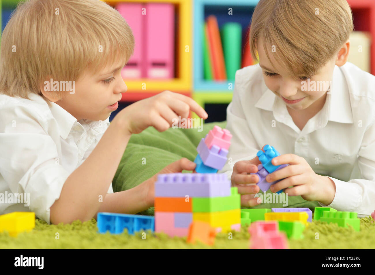 Two boys playing with colorful plastic blocks on floor Stock Photo - Alamy