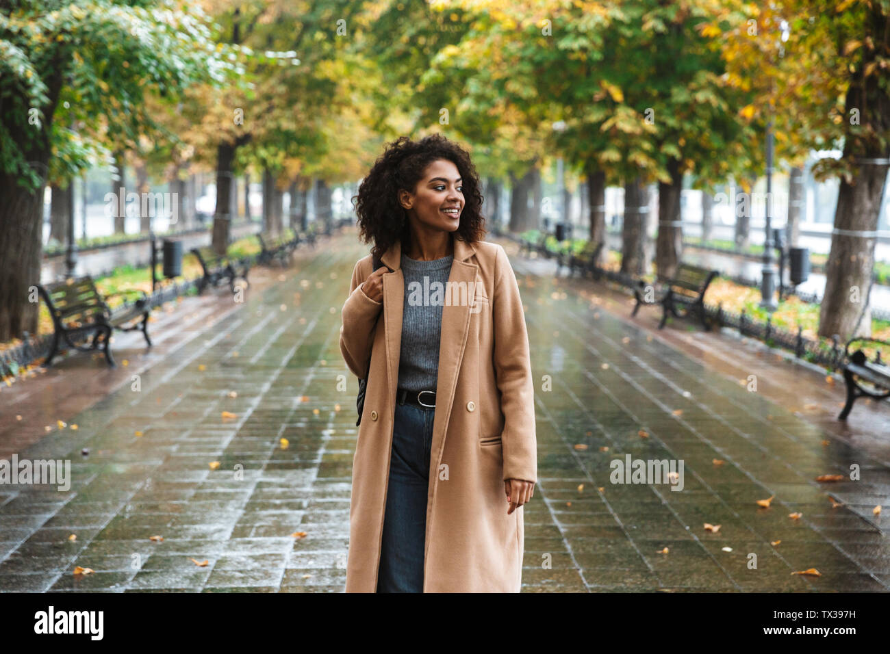Beautiful Young African Woman Wearing Coat Walking Outdoors At The Park