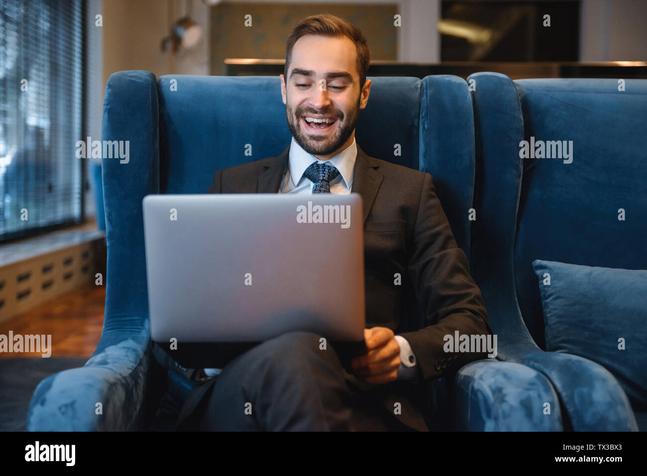 Handsome young businessman wearing suit sitting at the hotel lobby ...