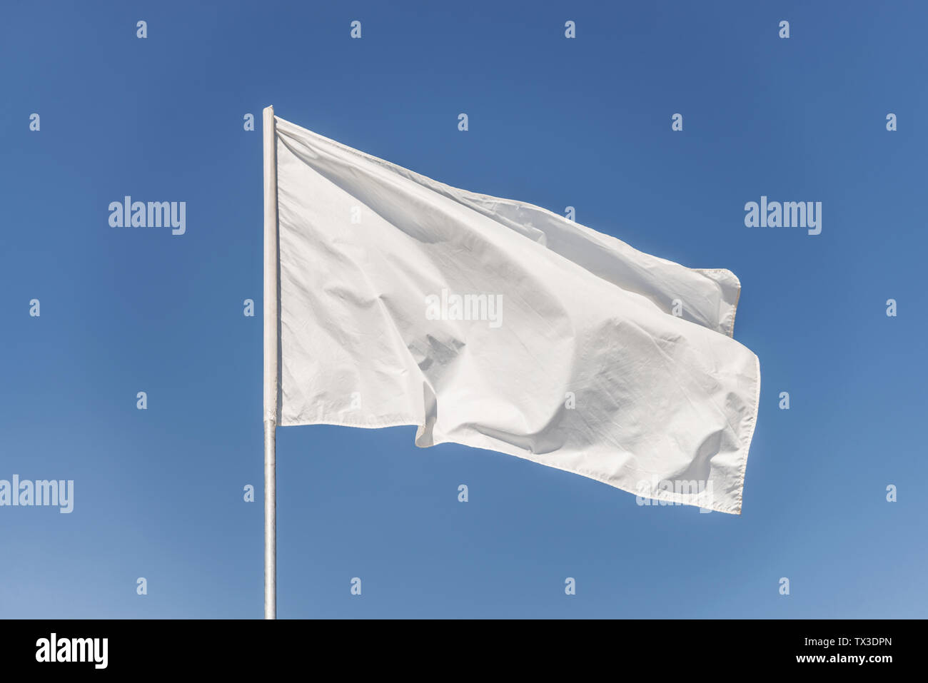 White flag against the blue sky fluttering in the wind Stock Photo - Alamy