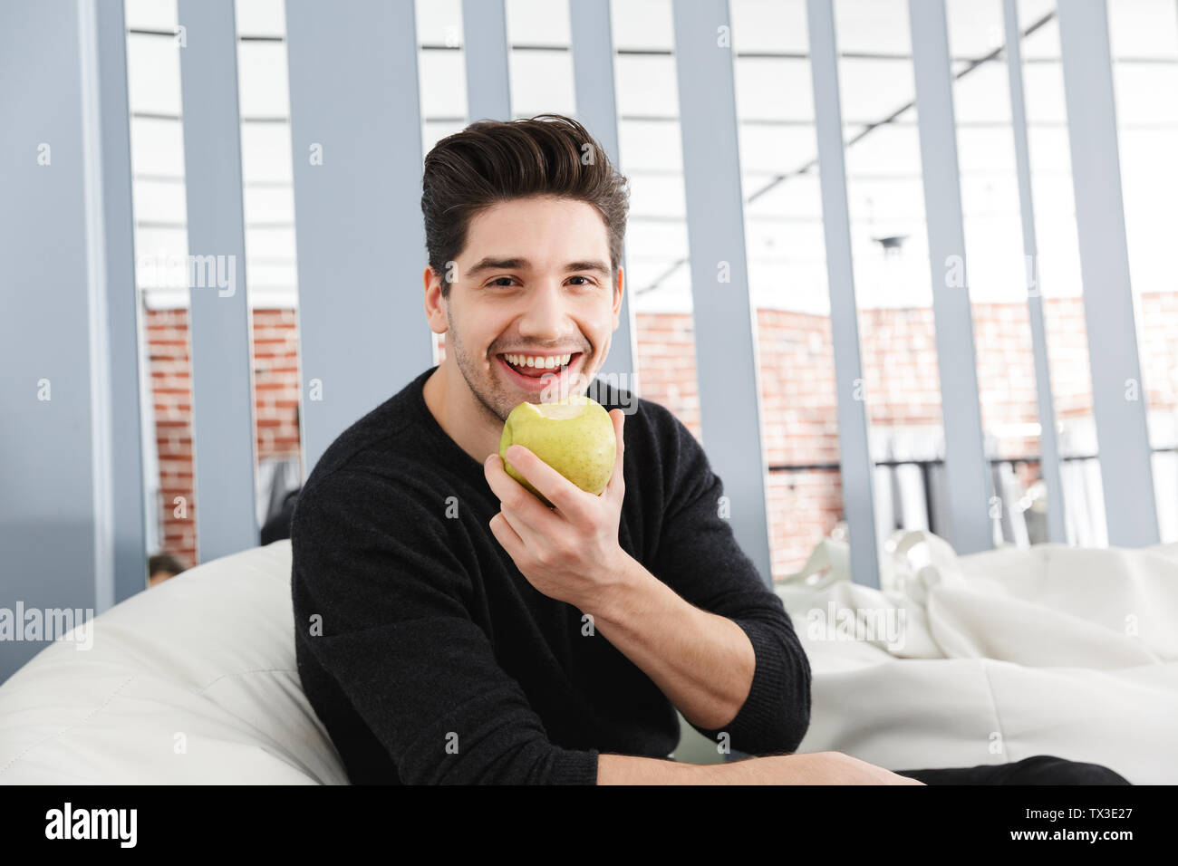 Image of a happy handsome young man at home indoors using laptop ...