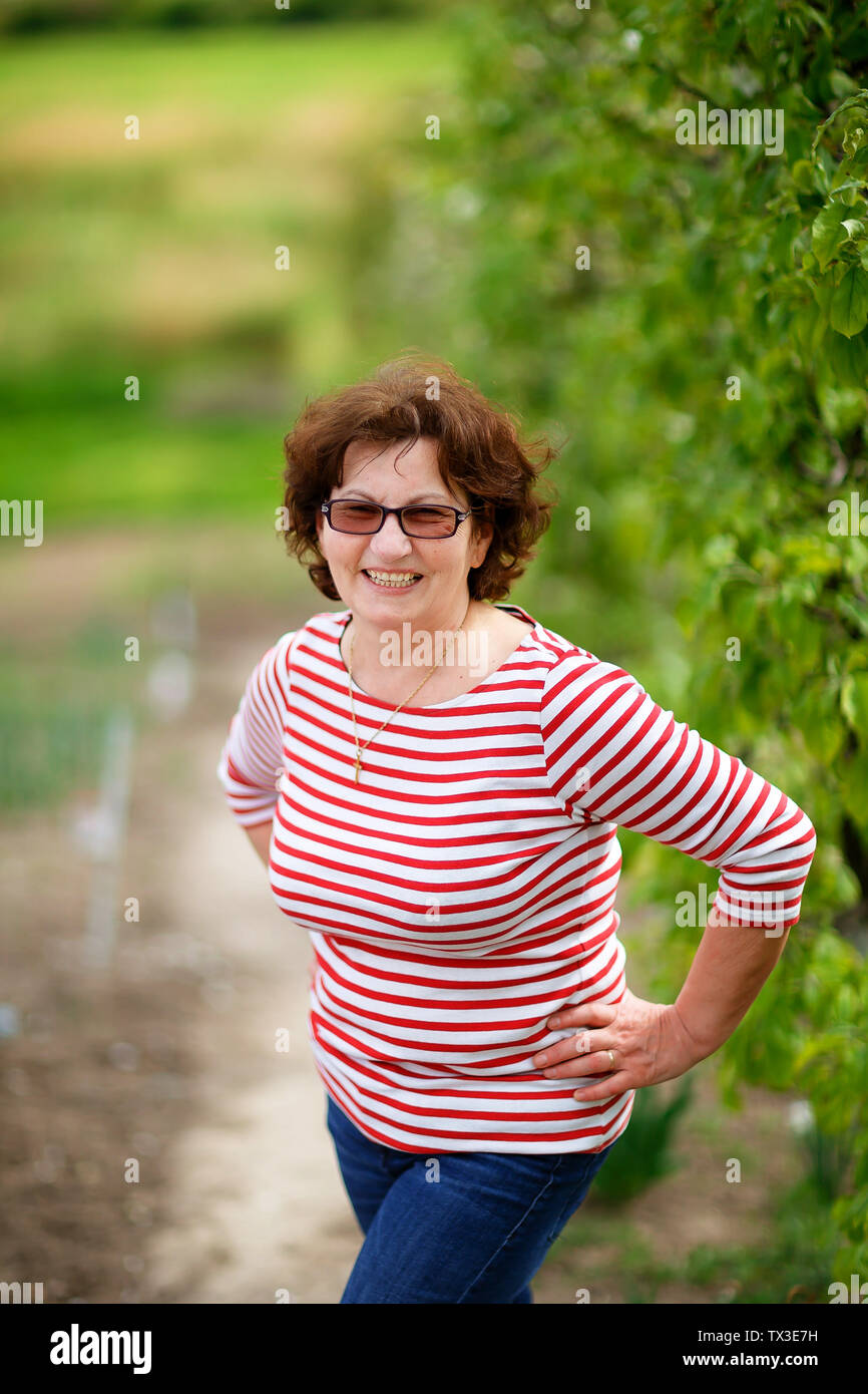 Grandmother in the orchard in summer. Stock Photo