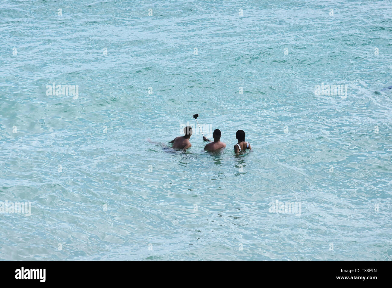 Tourists with selfie stick swimming ocean, taking selfie, Tulum, Mexico Stock Photo