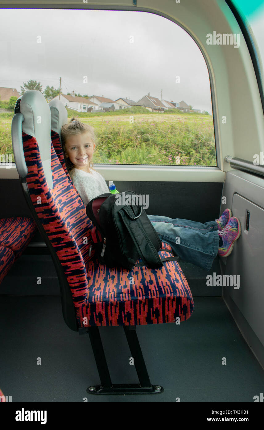 Young little girl sitting on the bus, smiling happily. Stock Photo