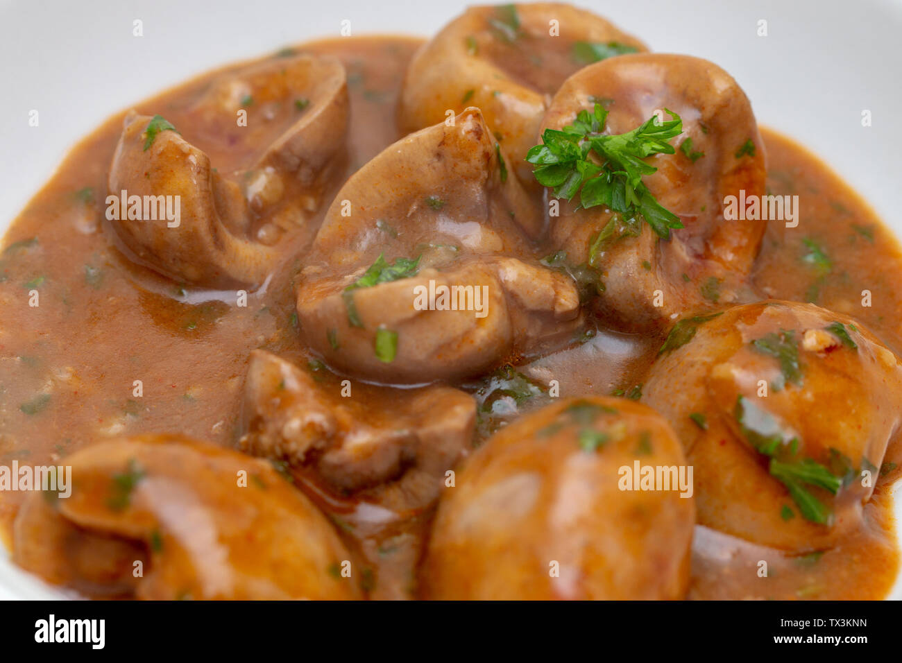 Close-up view of devilled (spicy) lambs' kidneys, in a brown sauce with chopped fresh parsley, an old-fashioned British breakfast dish. Stock Photo