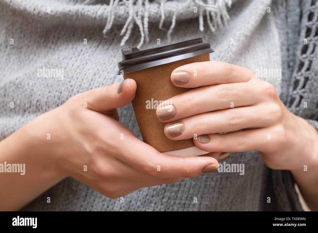 Paper cup with coffee in female hands. Stock Photo