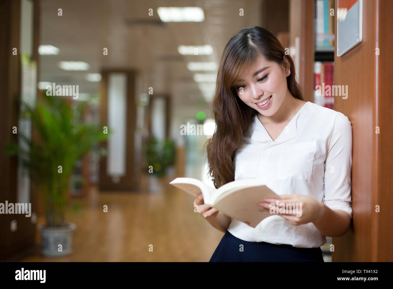 Asian beautiful female student holding book in library Stock Photo - Alamy