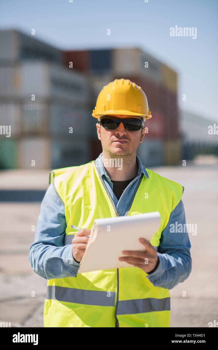 Portrait of a worker with a notepad near cargo containers on industrial site Stock Photo