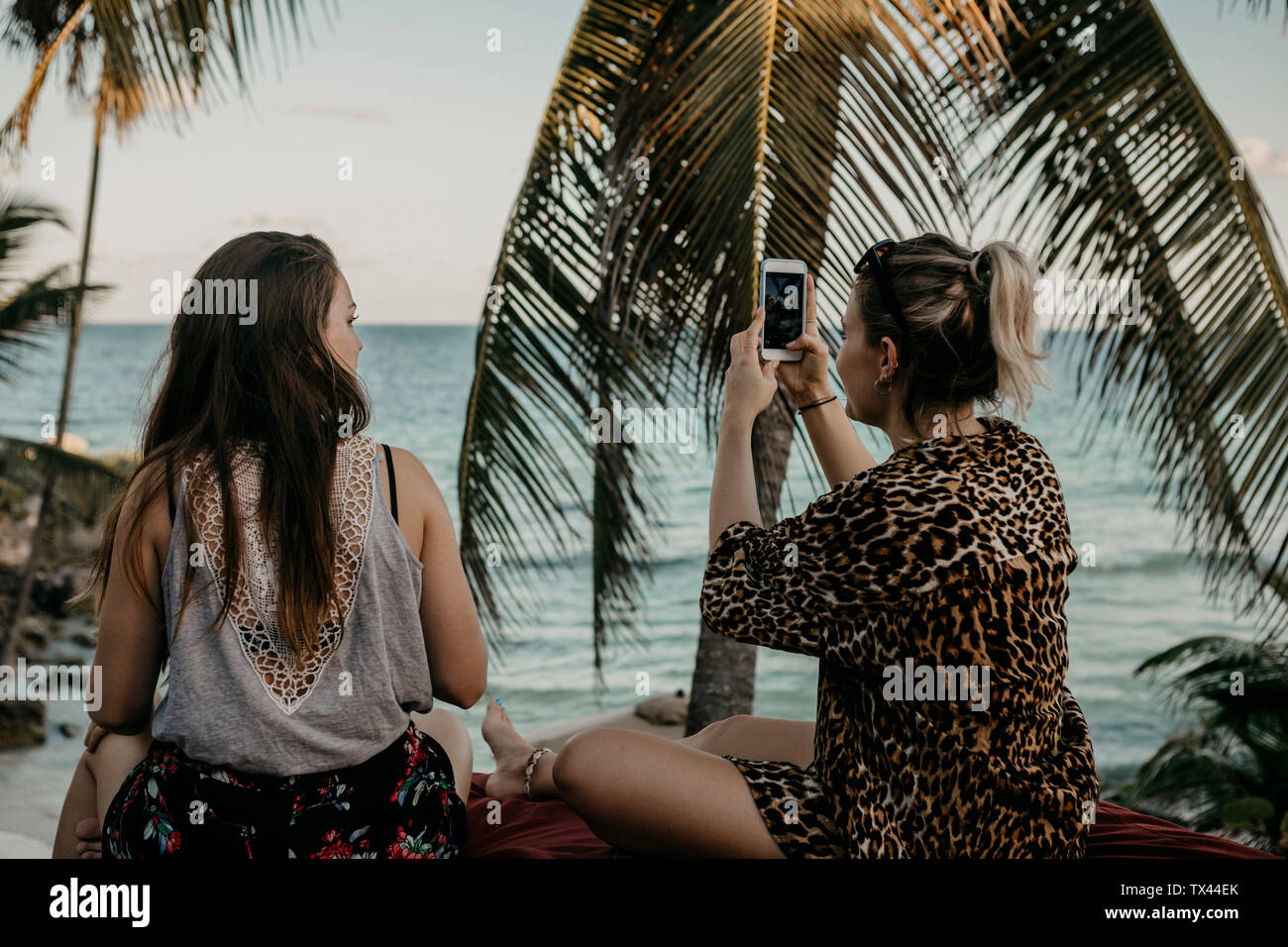Mexico, Quintana Roo, Tulum, two young women with cell phone relaxing on the beach Stock Photo