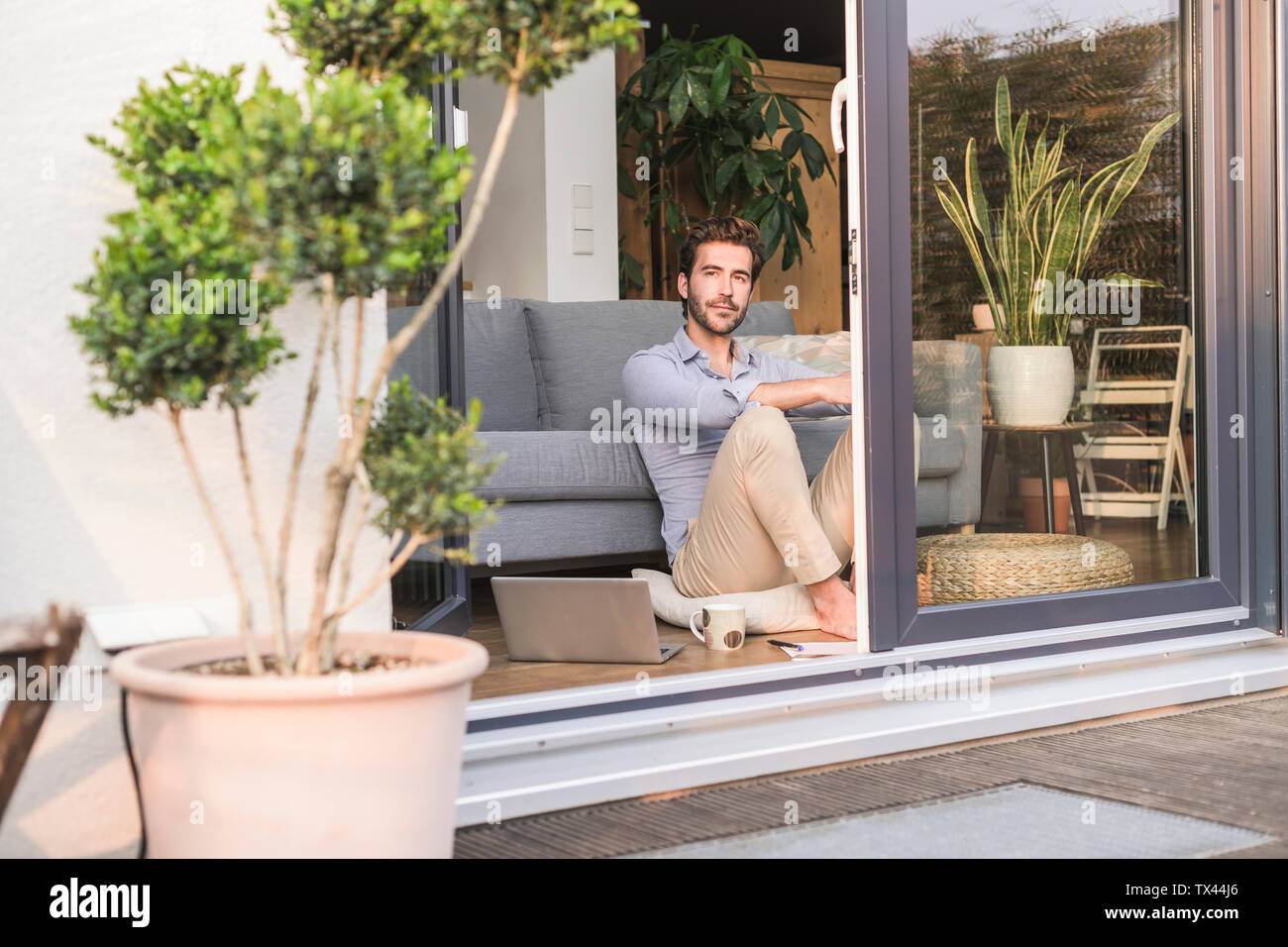 Young man relaxing in his comfortable home, looking out of window Stock Photo
