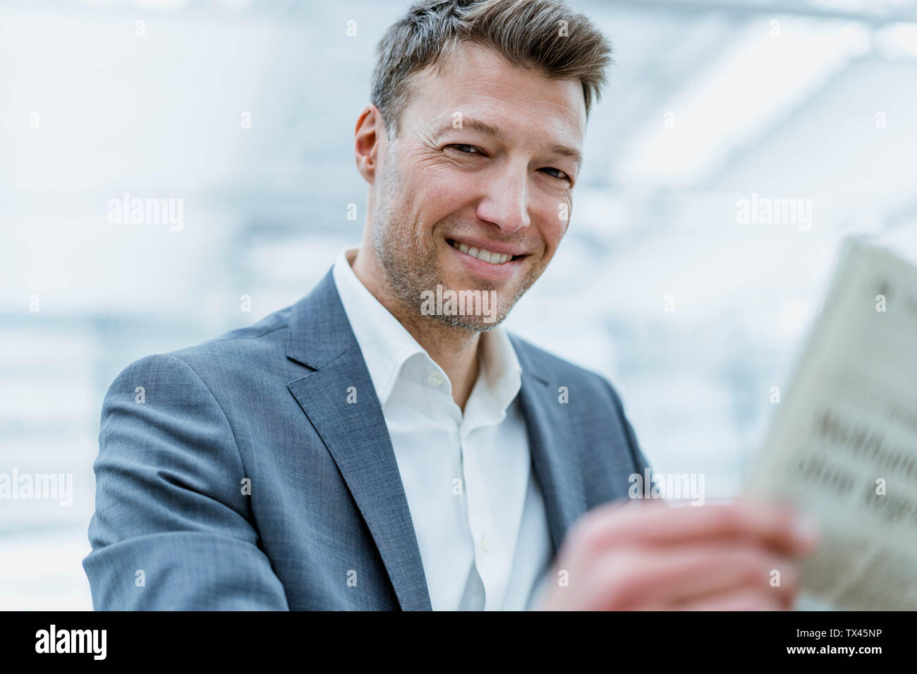 Portrait of smiling  businessman reading newspaper Stock Photo