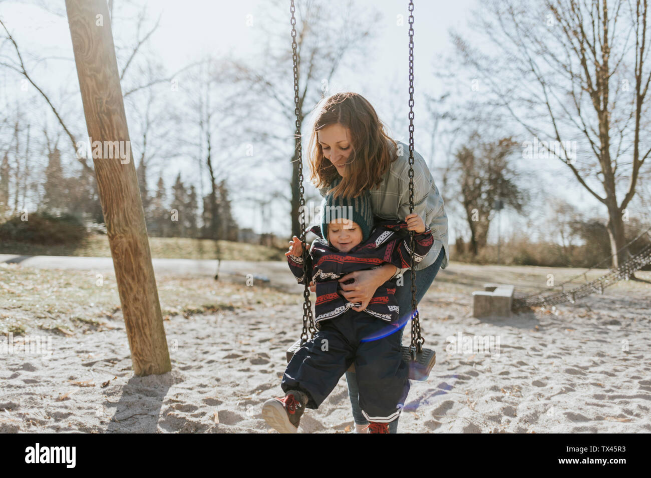 Mother with little daughter on swing on a playground Stock Photo