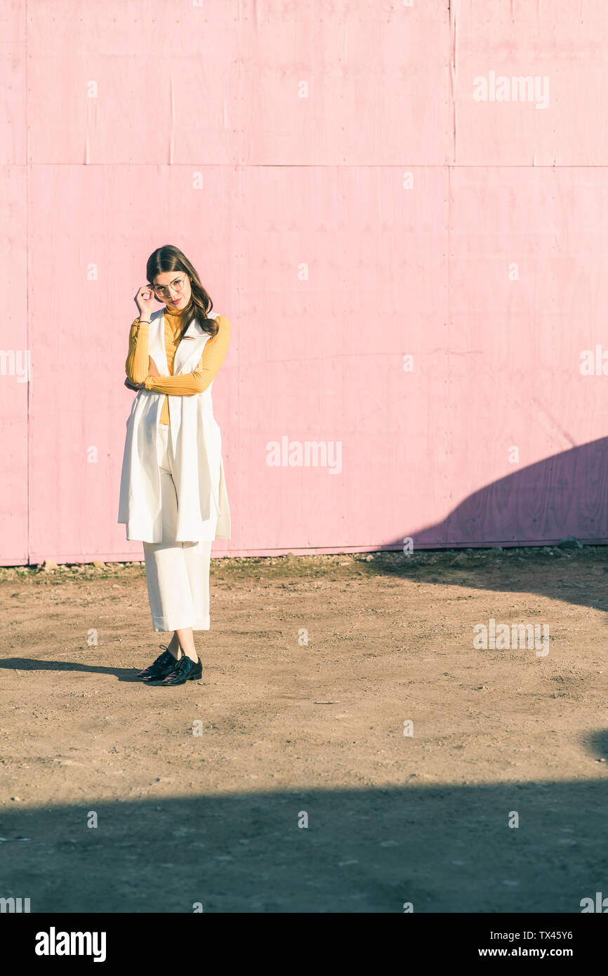 Confident young woman standing in front of a pink wall Stock Photo - Alamy
