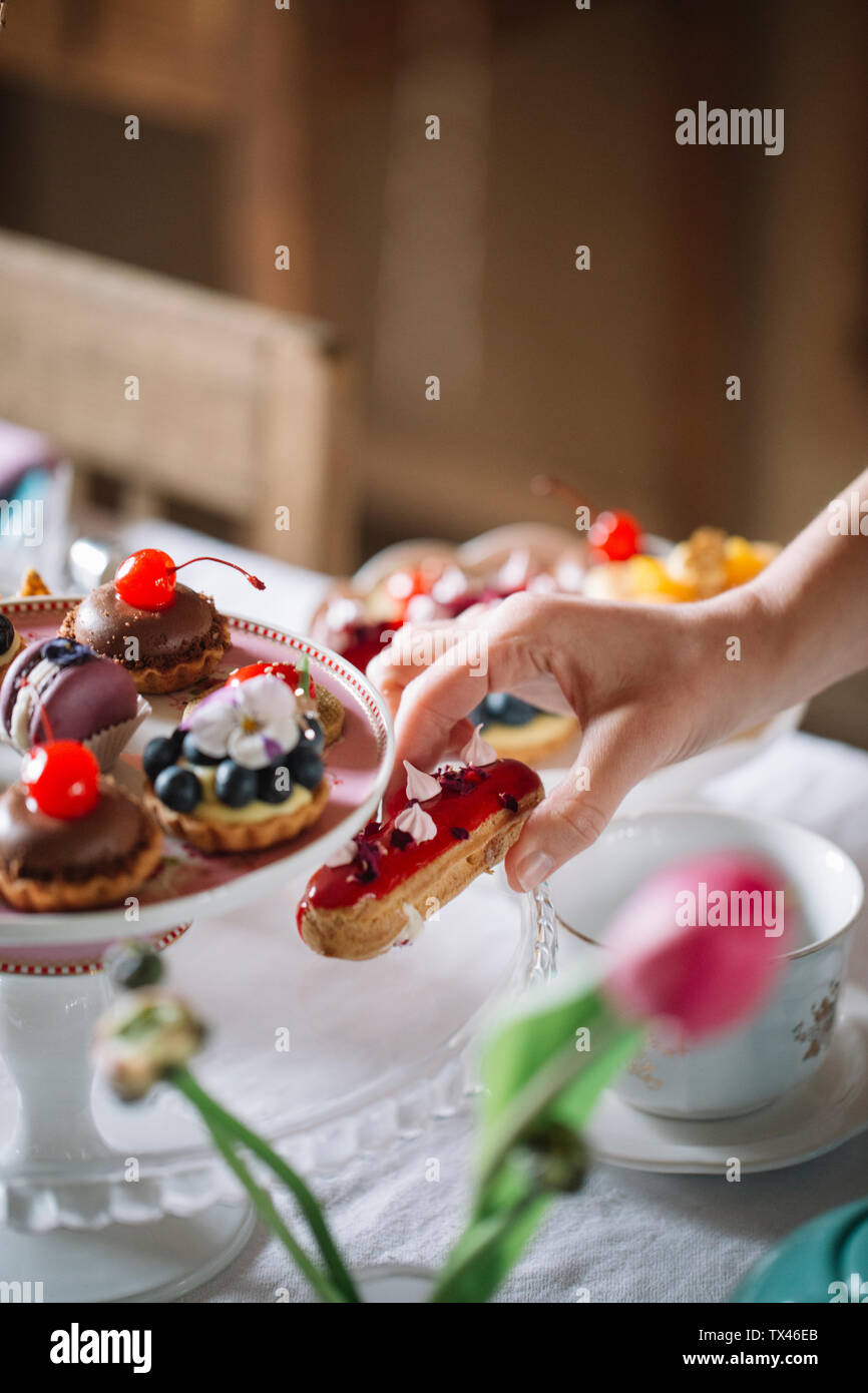 Woman's hand putting Eclair on cake stand Stock Photo