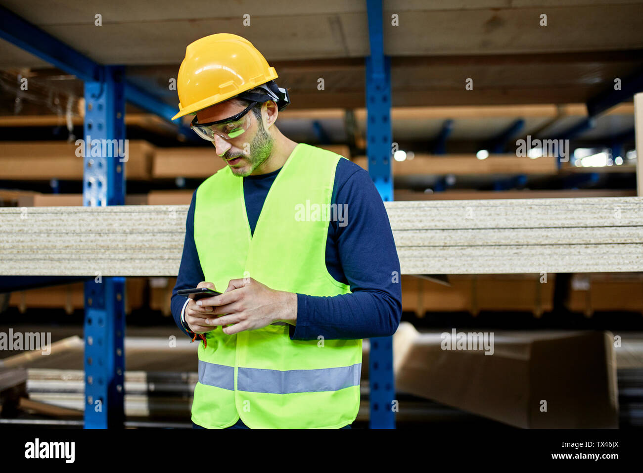 Worker using cell phone in factory warehouse Stock Photo - Alamy