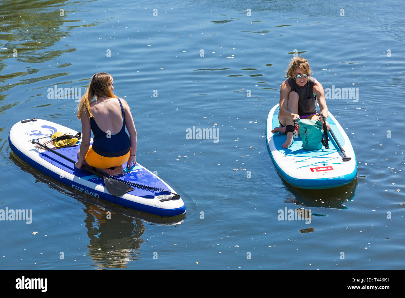 Woman paddleboarders paddle boarders relaxing on paddleboards paddle boards on Dorset Dinghy Day at River Stour, Iford, Dorset UK in June Stock Photo