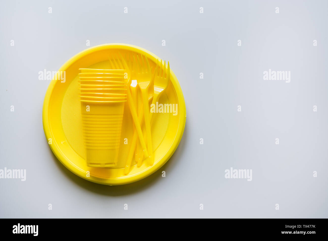Single use picnic yellow utensils on grey. Environment, eco friendly, plastic garbage for recycle concept. Top view. Space for text. Flat lay. Stock Photo