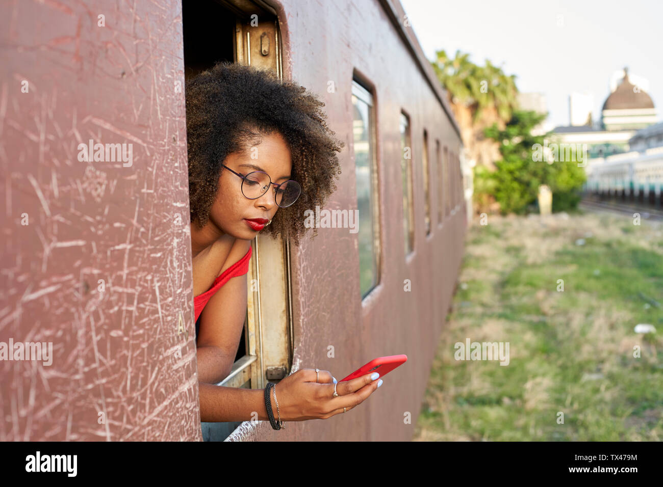 Young woman checking her phone at the window of a train Stock Photo