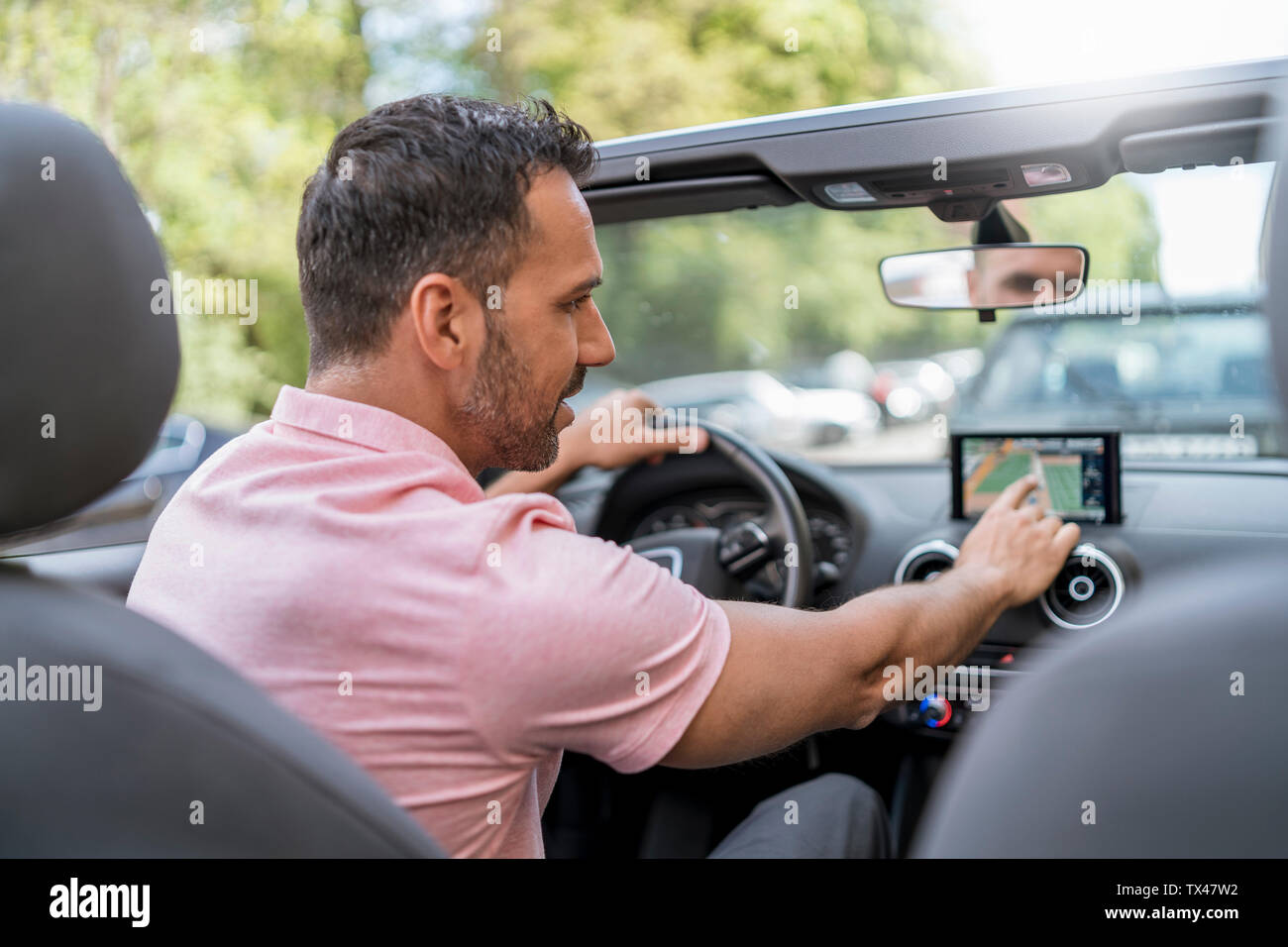 Man driving convertible using route guidance system Stock Photo