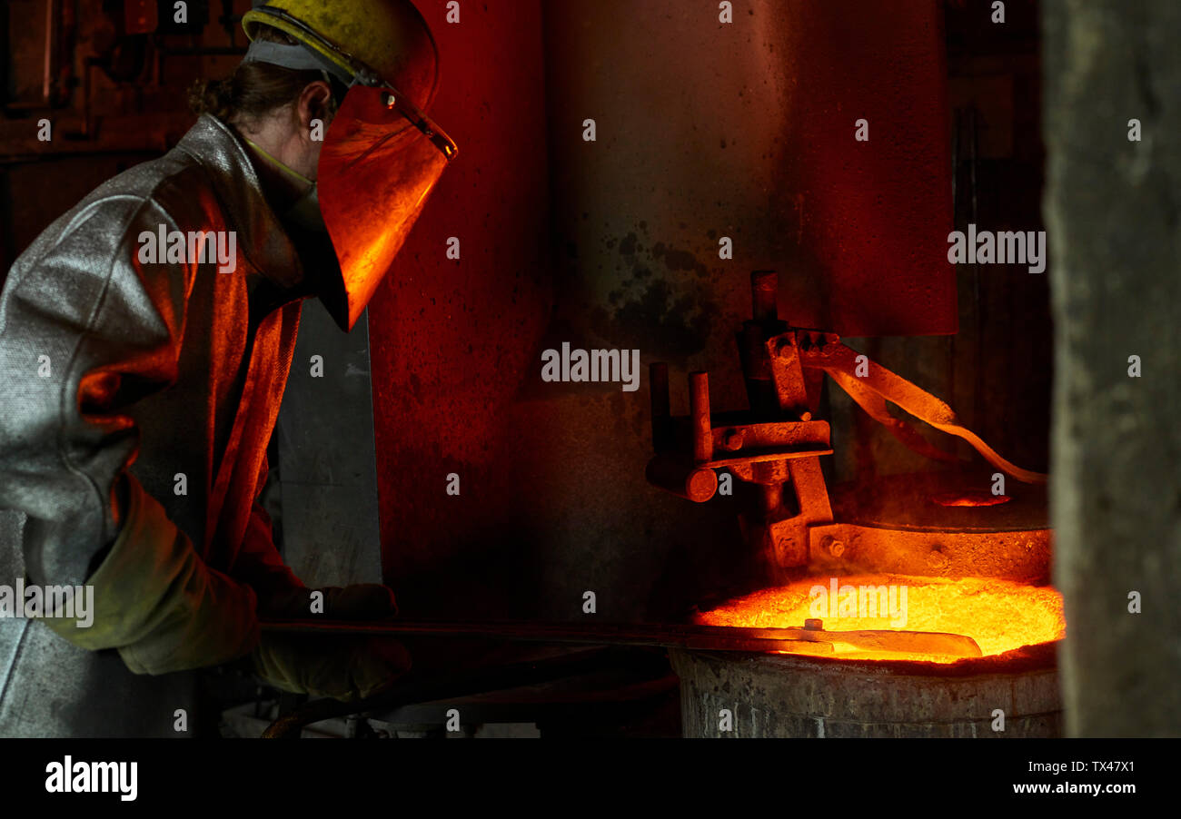 Industry, worker at furnace during melting copper, wearing a fire proximity suit Stock Photo