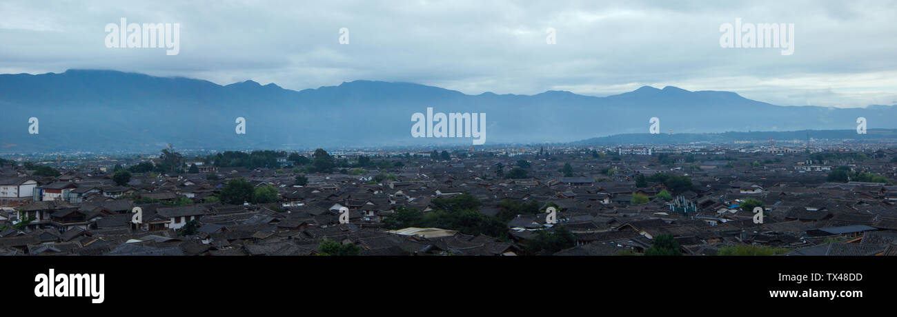 A panoramic view of the main town of Lijiang ancient town. Located in the old town of Lijiang in Yunnan, China. Old towns and mountains and clouds Stock Photo