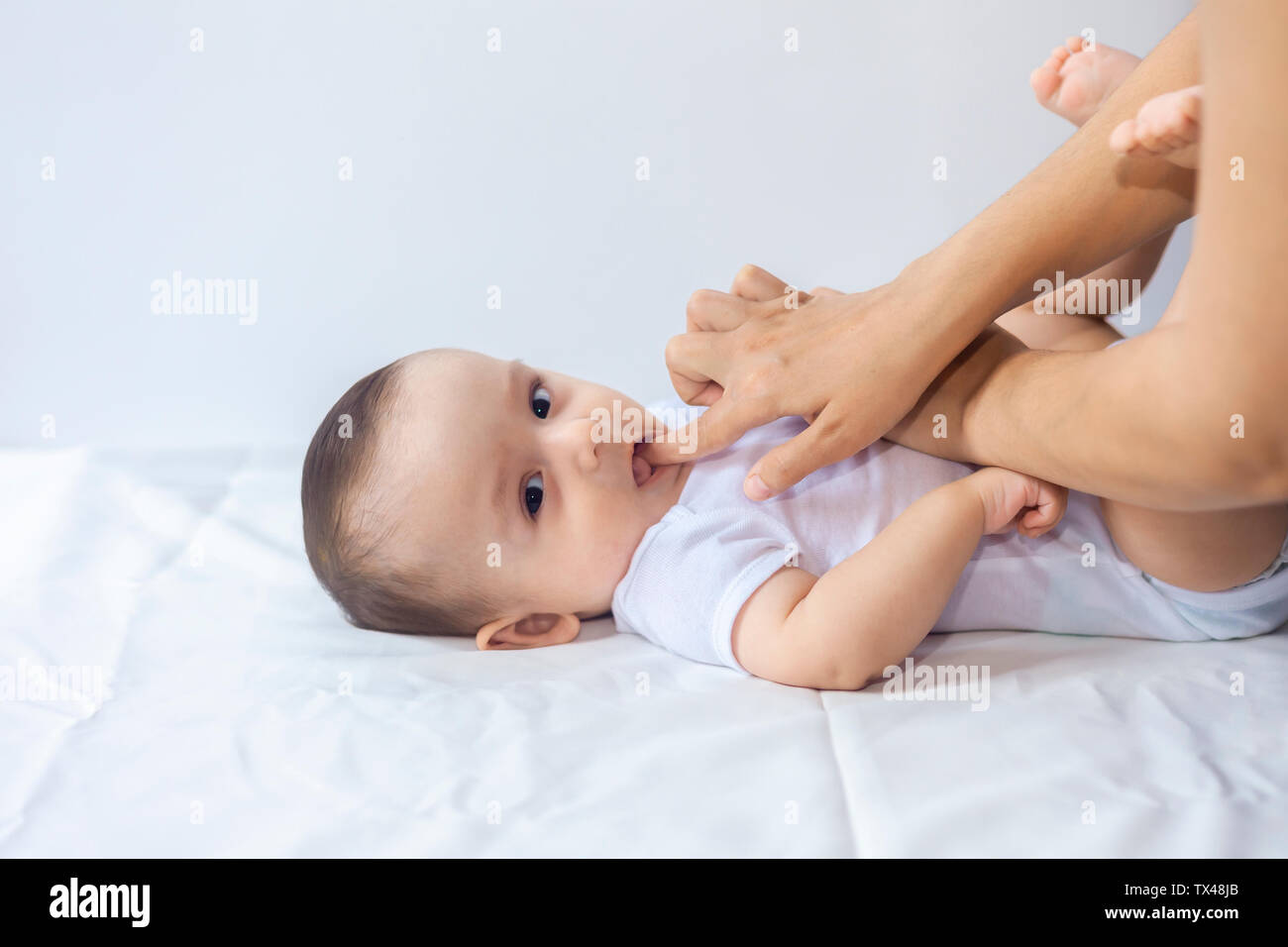Baby boy teething pain. Little 6-month baby having teeth pains. Mother rubbing gel to her little baby boy's teeth. Medicine and health concept. Stock Photo