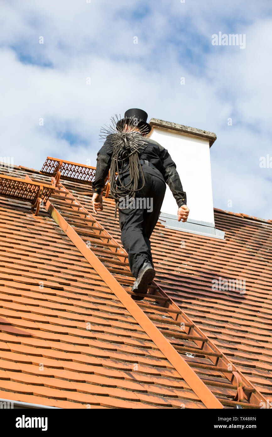 Chimney sweep climbing up house roof Stock Photo