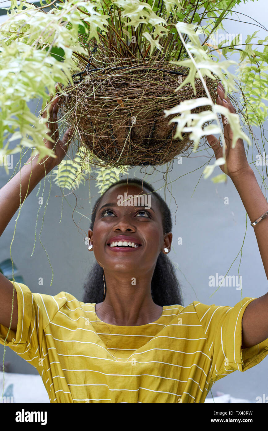 Happy young woman holding a plant Stock Photo - Alamy