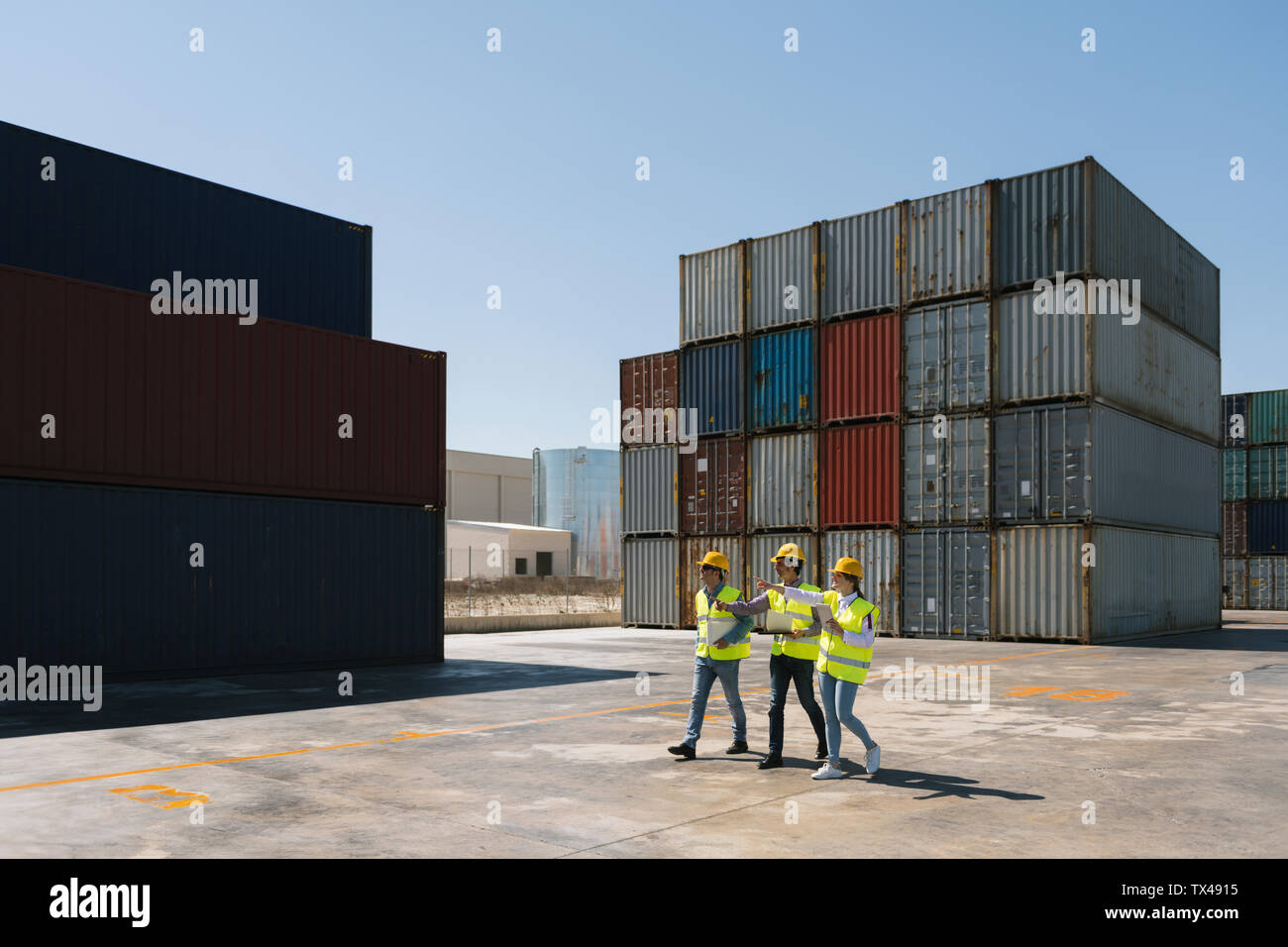 Workers walking together near stack of cargo containers on industrial ...