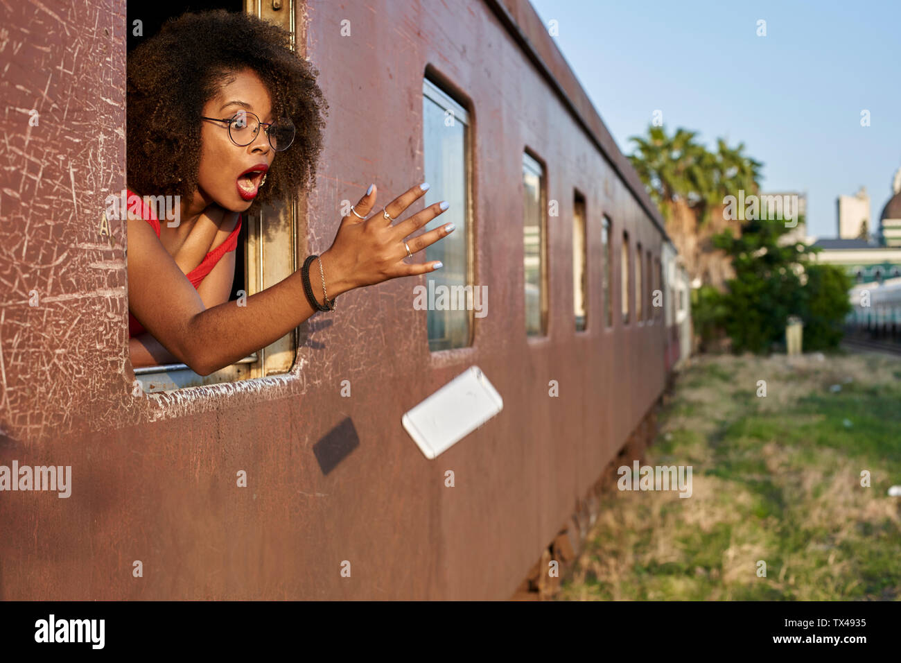 Woman's phone falling out of train window Stock Photo
