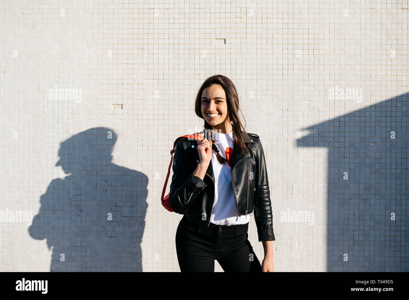 Happy young woman with a red hip bag, wall in the background Stock Photo