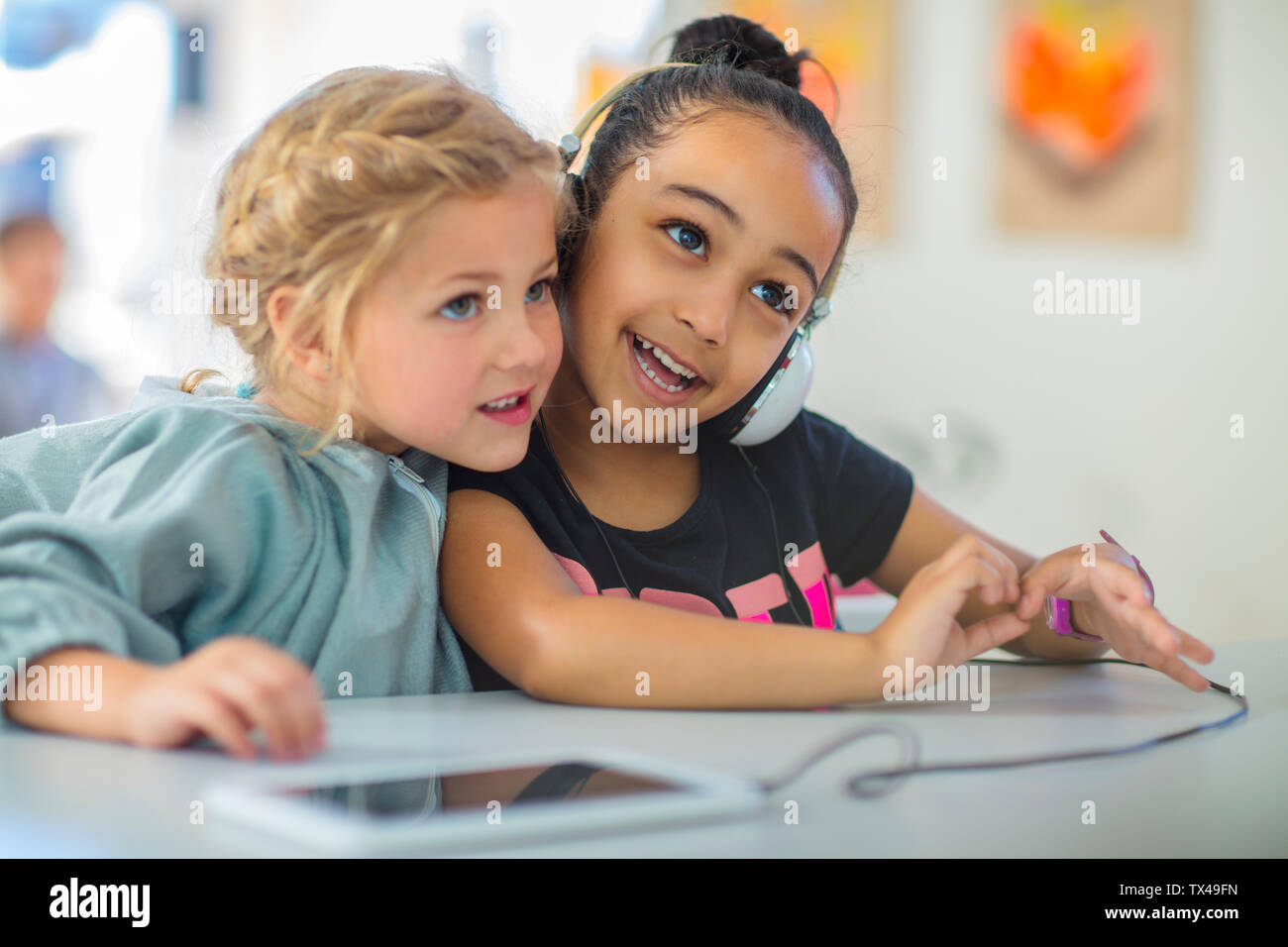 Two girls sharing headphones in kindergarten Stock Photo