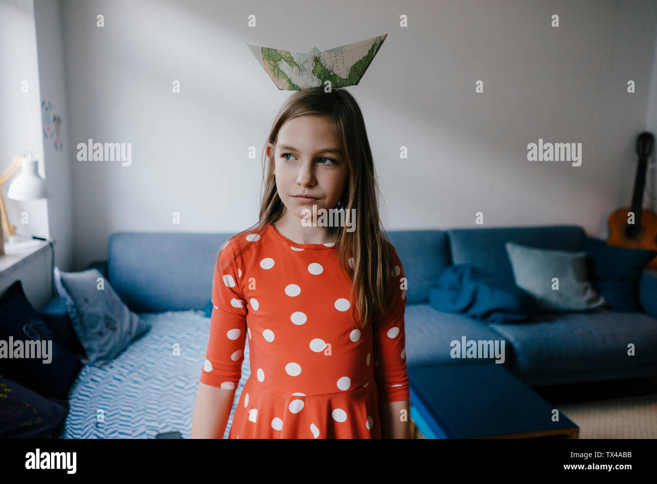 Girl balancing paper boat on her head at home Stock Photo